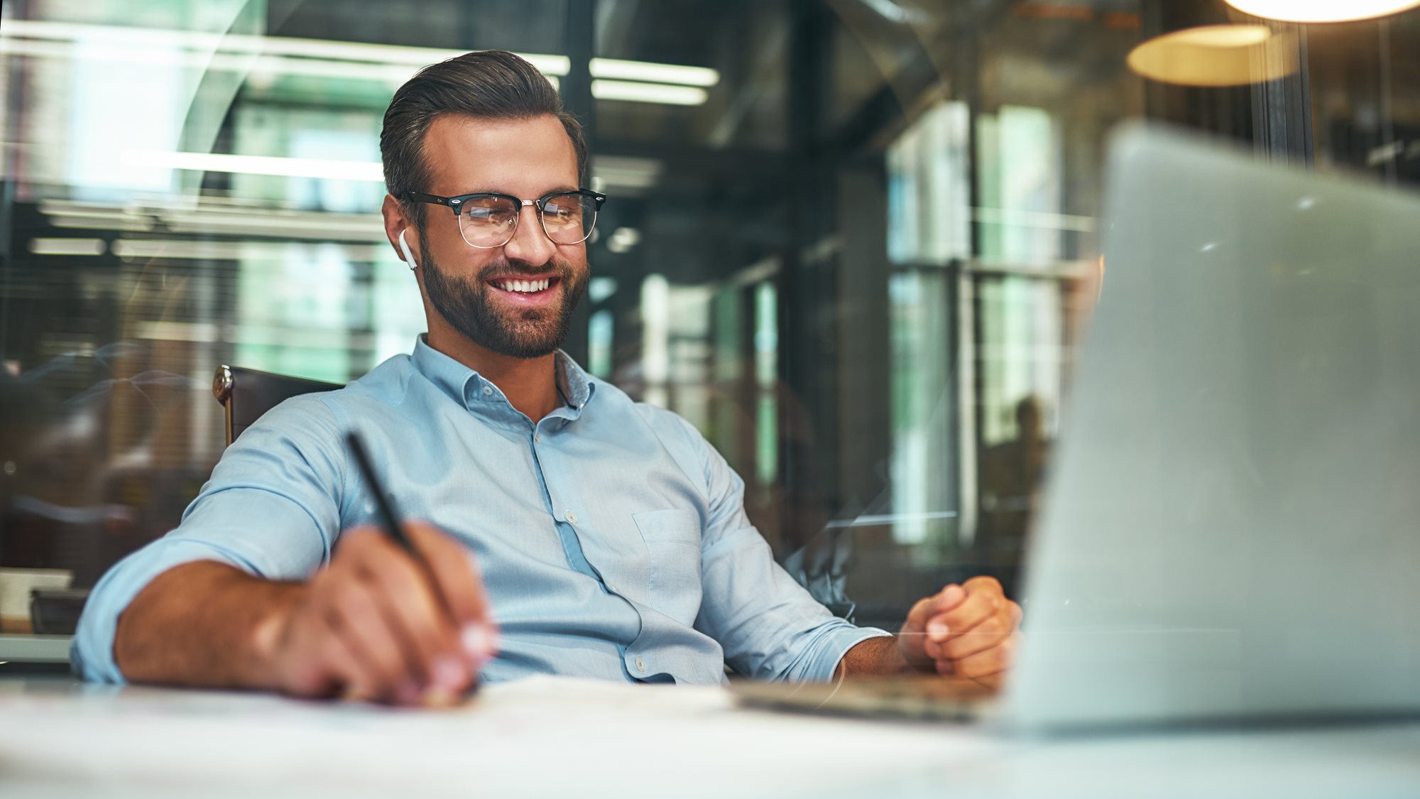 A young professional smiling while he does his work at a desk.